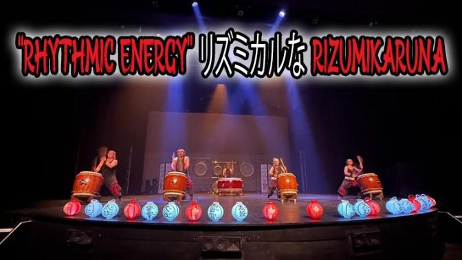 Taiko drummers performing their traditional red drums on a stage decorated with blue and red paper lanterns