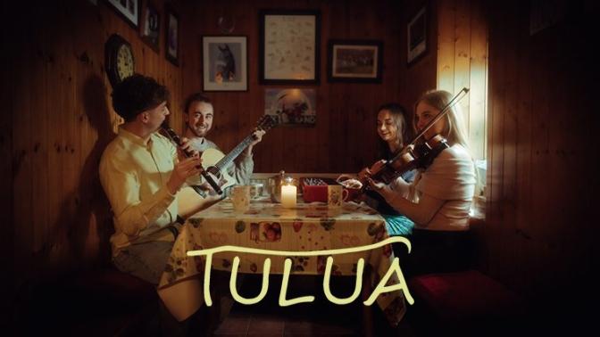 Irish band Tulua, 4 musicians holding their instruments a fiddle guitar flute and keyboard seated at a kitchen table