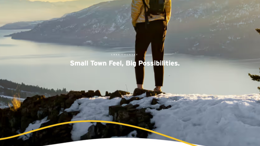 person standing on snowy mountaintop looking over Lake Country and Okanagan Lake