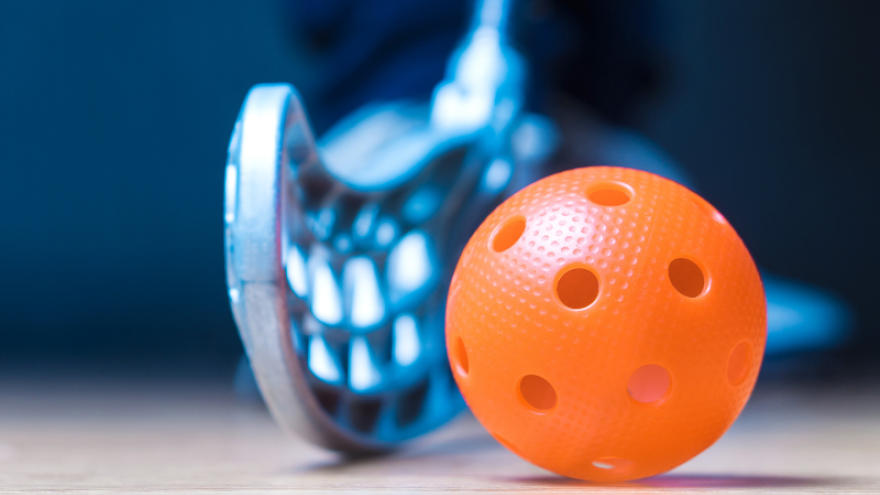 Floor hockey stick and ball with holes in it