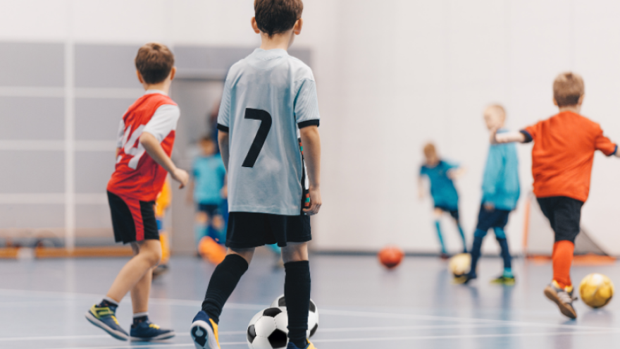 Young children practicing soccer indoors
