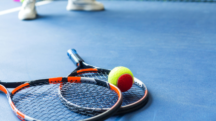 Two rackets and ball lay on a tennis court