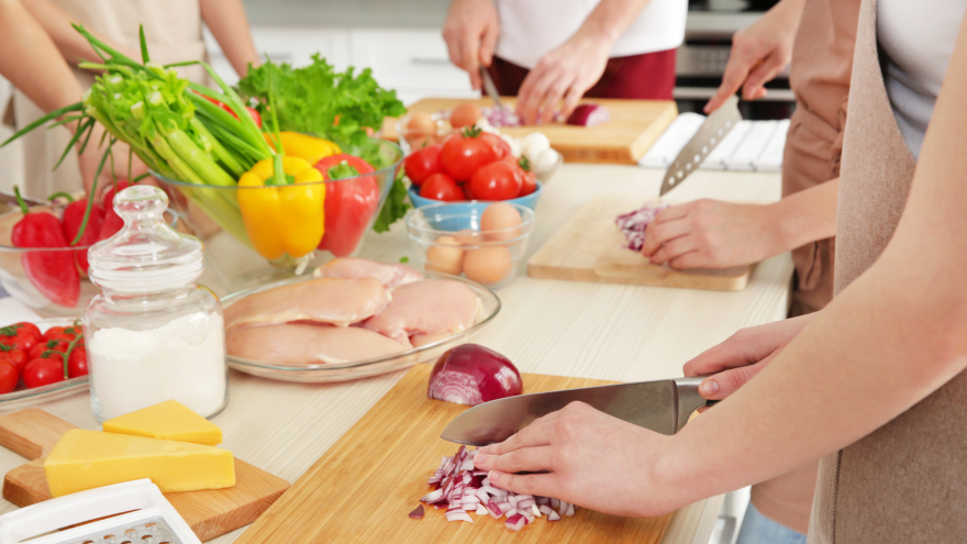 a person chopping red onion with other people around a table