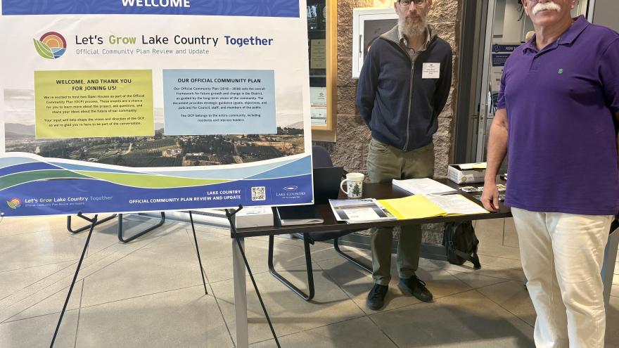 Mayor and Planner stand beside sign welcoming public to open house