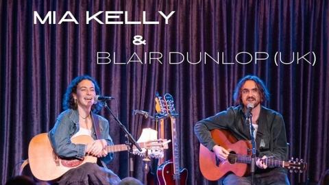Mia Kelly and Blair Dunlop on stage seated and playing guitar