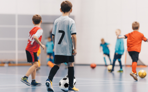 Young children practicing soccer indoors