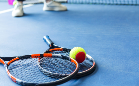 Two rackets and ball lay on a tennis court