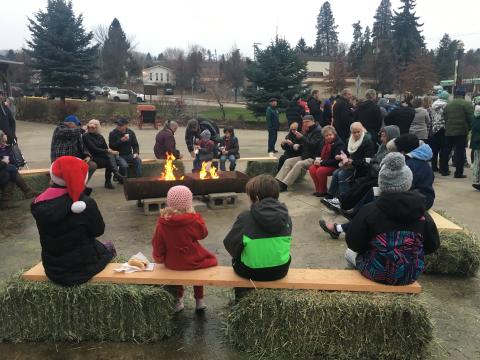 Community members enjoy hot chocolate and Christmas songs around a fire pit at Memorial Park