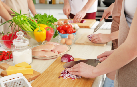a person chopping red onion with other people around a table