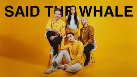 three members of musical group "said the whale" seated together while one member stands in an artistic portrait on a yellow background