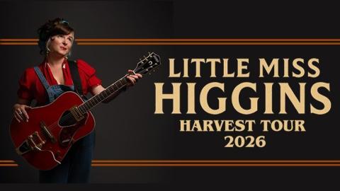 country blues artist little miss higgins posed with her guitar, wearing a red top and denim overalls, looking skyward