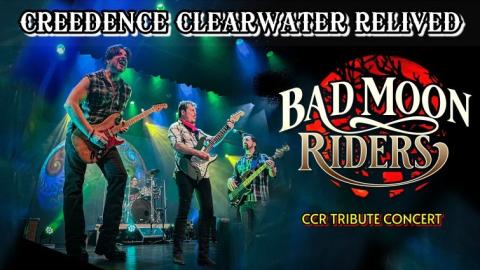 Tribute Band Bad Moon Riders performing on stage with their guitars and green and blue spotlights shining through dry ice fog