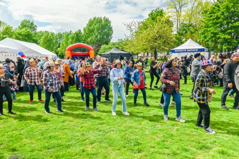 group of people outside in a park learning line dancing steps