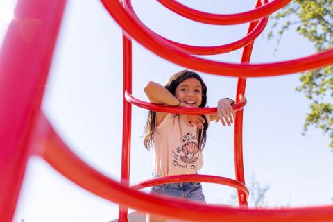 A young girl plays on a jungle gym