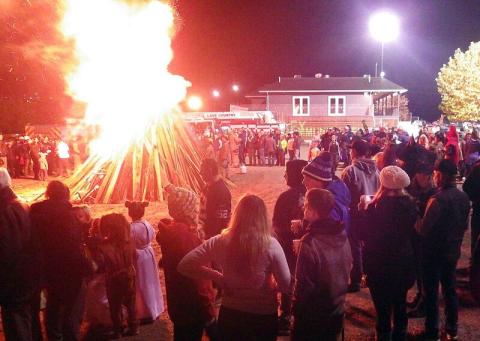 Halloween bonfire with community members watching
