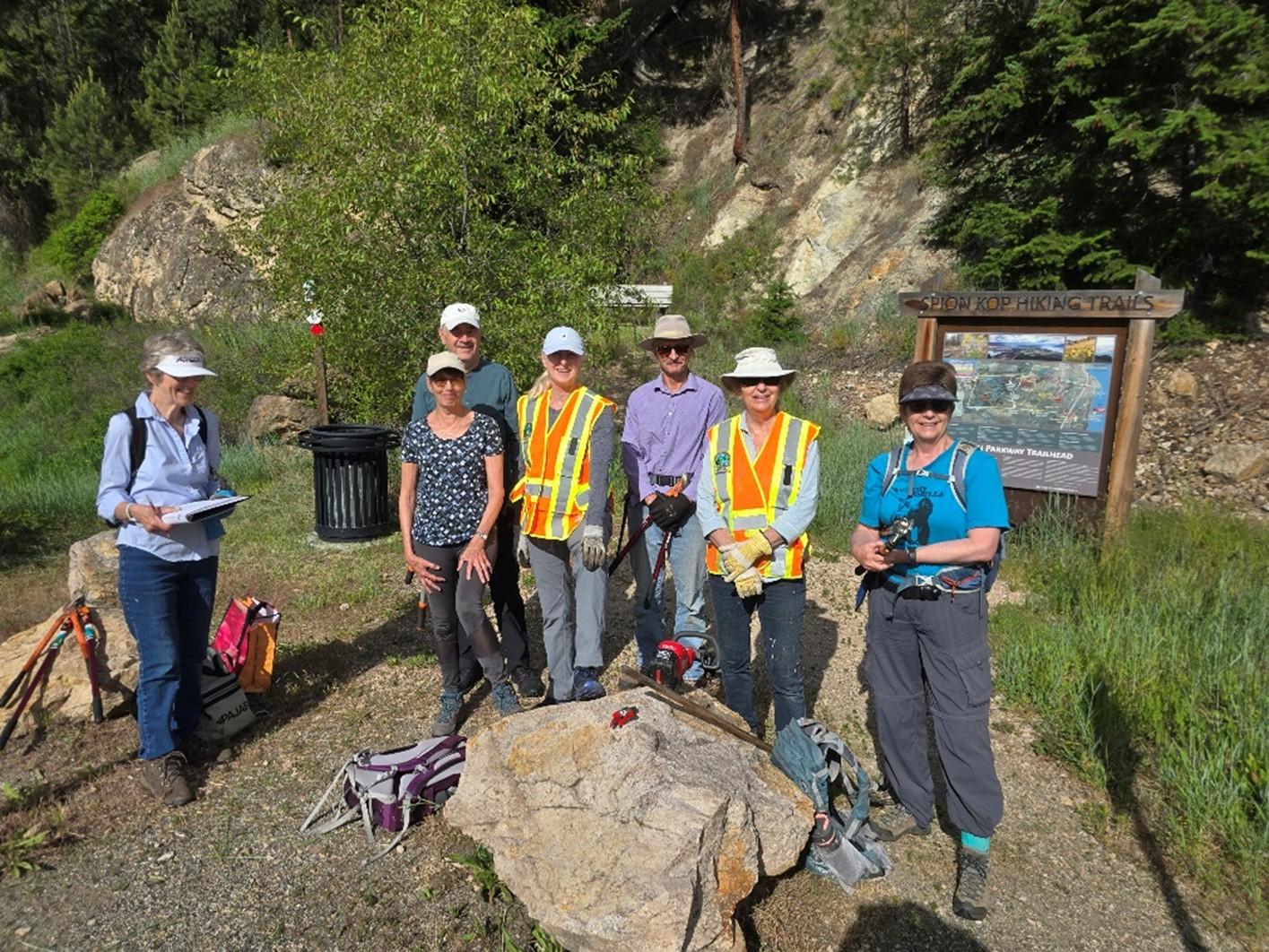 a trail maintenance group of volunteers stands by the Spion Kop trails sign
