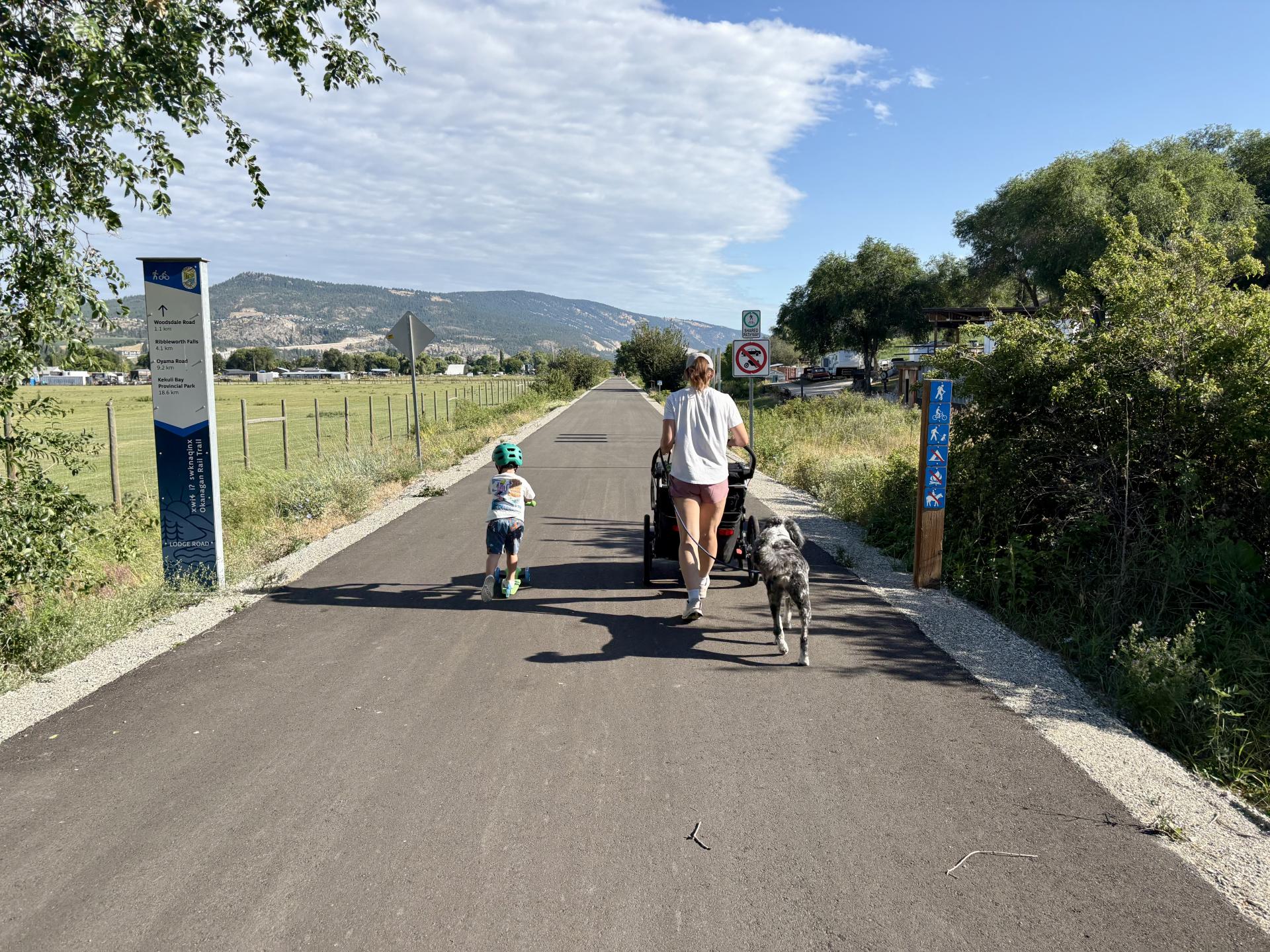 family with dog and child on bike uses new paved section of Okanagan Rail Trail