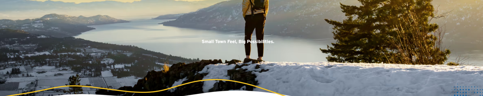 person standing on snowy mountaintop looking over Lake Country and Okanagan Lake