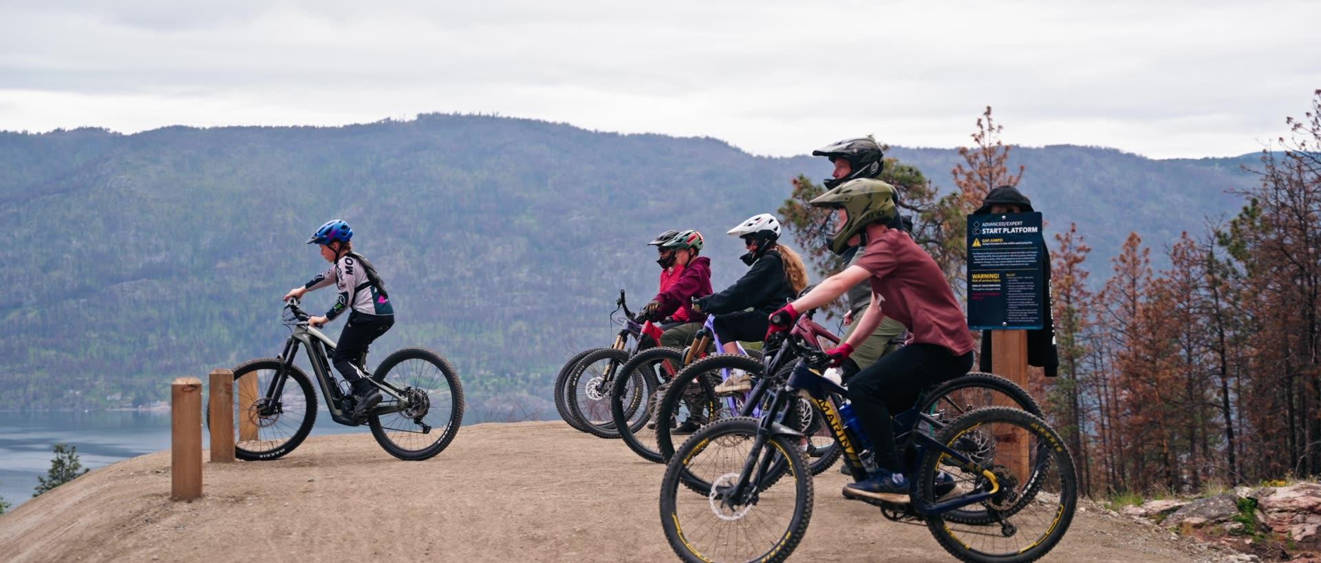 A group of youth on mountain bikes wait for their turn to ride at the start platform